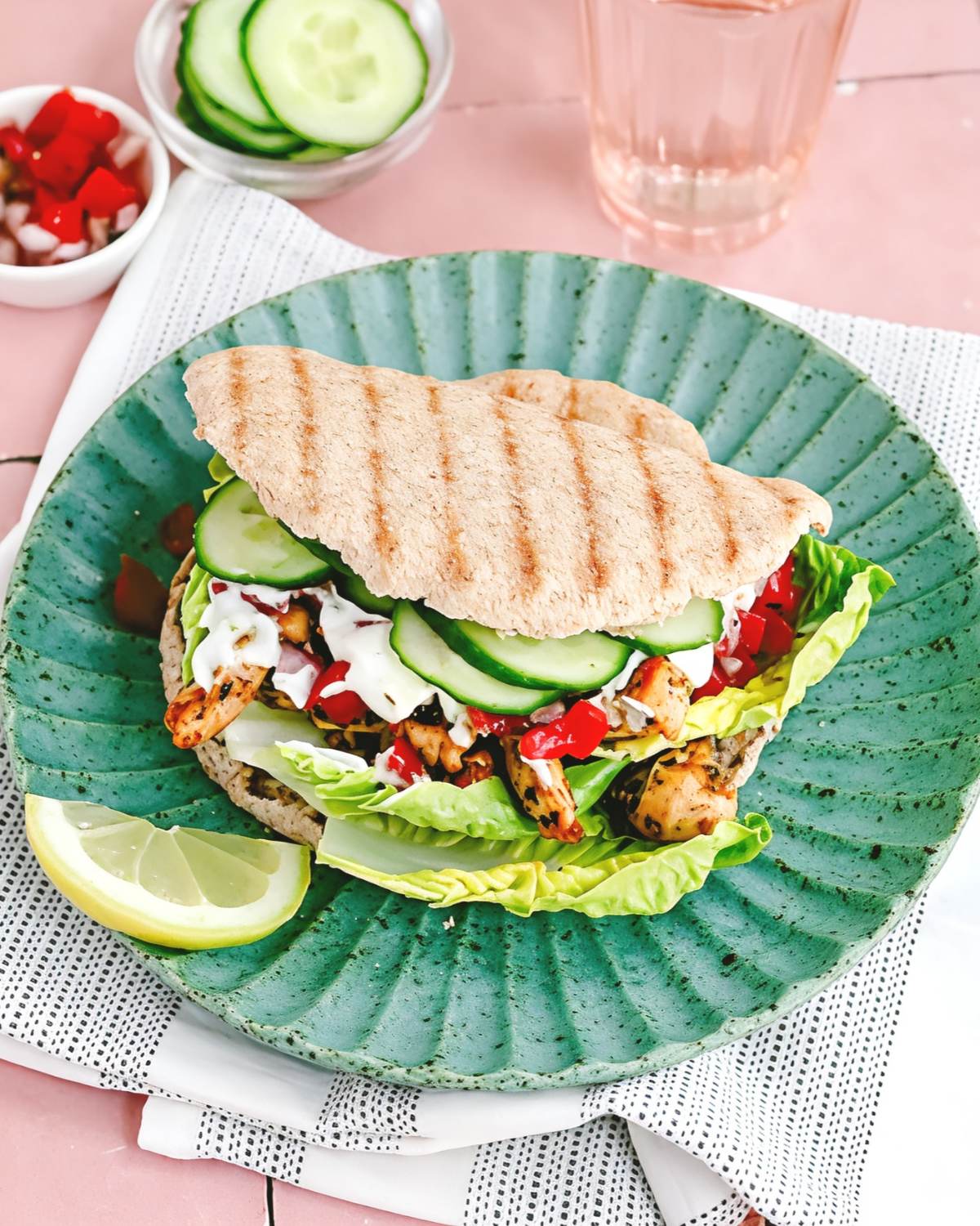 As an SEO expert, here is your optimized Alt text (along with file name and title recommendations) for this image to maximize your search rankings and accessibility.1. Primary SEO Alt TextPita pocket stuffed with grilled chicken, tomato salsa, lettuce, cucumber, and garlic sauce on a green plate