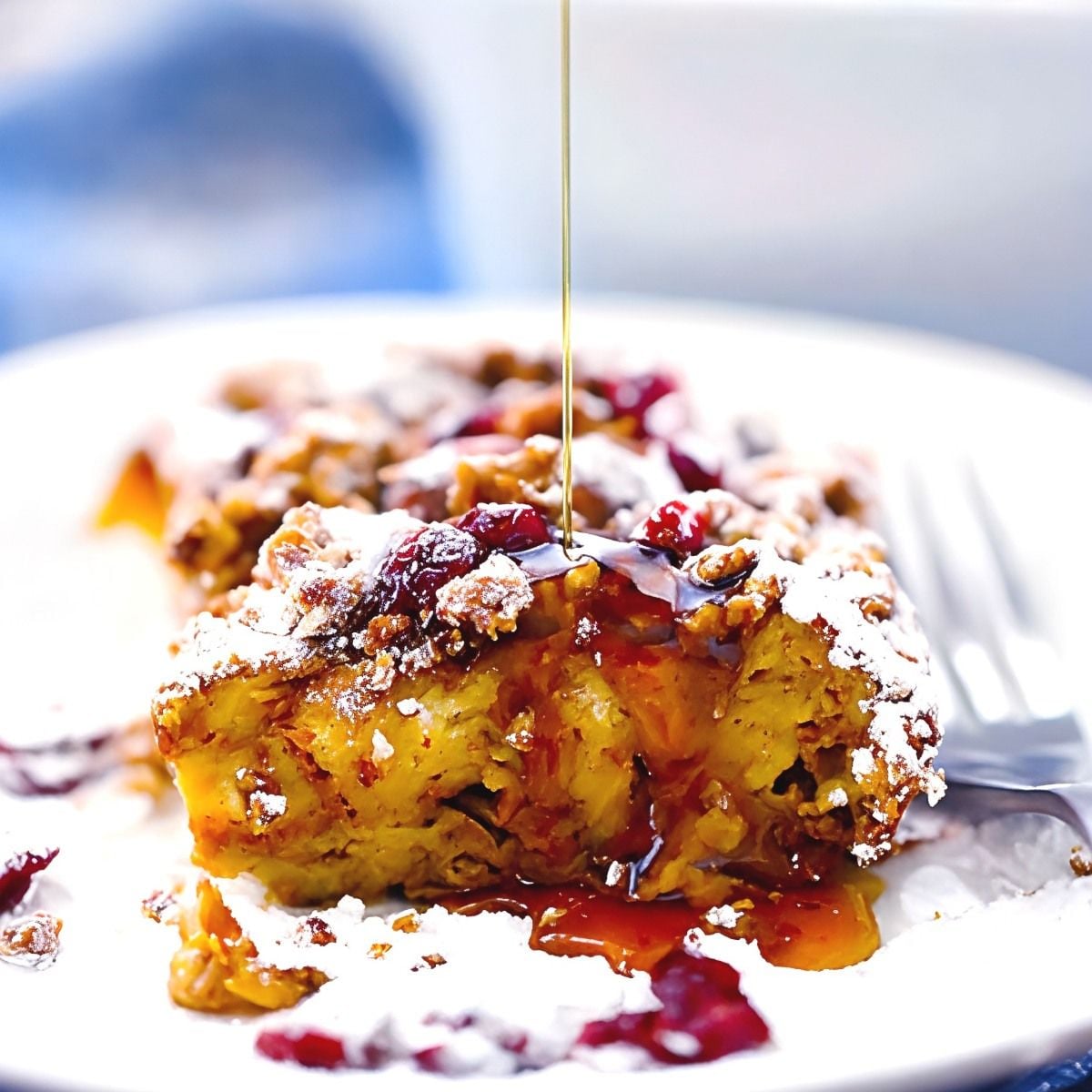 A slice of pumpkin french toast casserole dusted with powdered sugar and drizzled with syrup as Thanksgiving breakfast ideas.