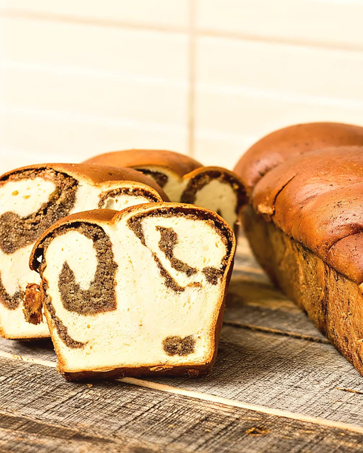 Thick slices of traditional Romanian Cozonac cu Nucă sweet brioche bread showcasing rich swirl patterns of walnut filling on a wooden surface, served as a festive European Christmas dessert.