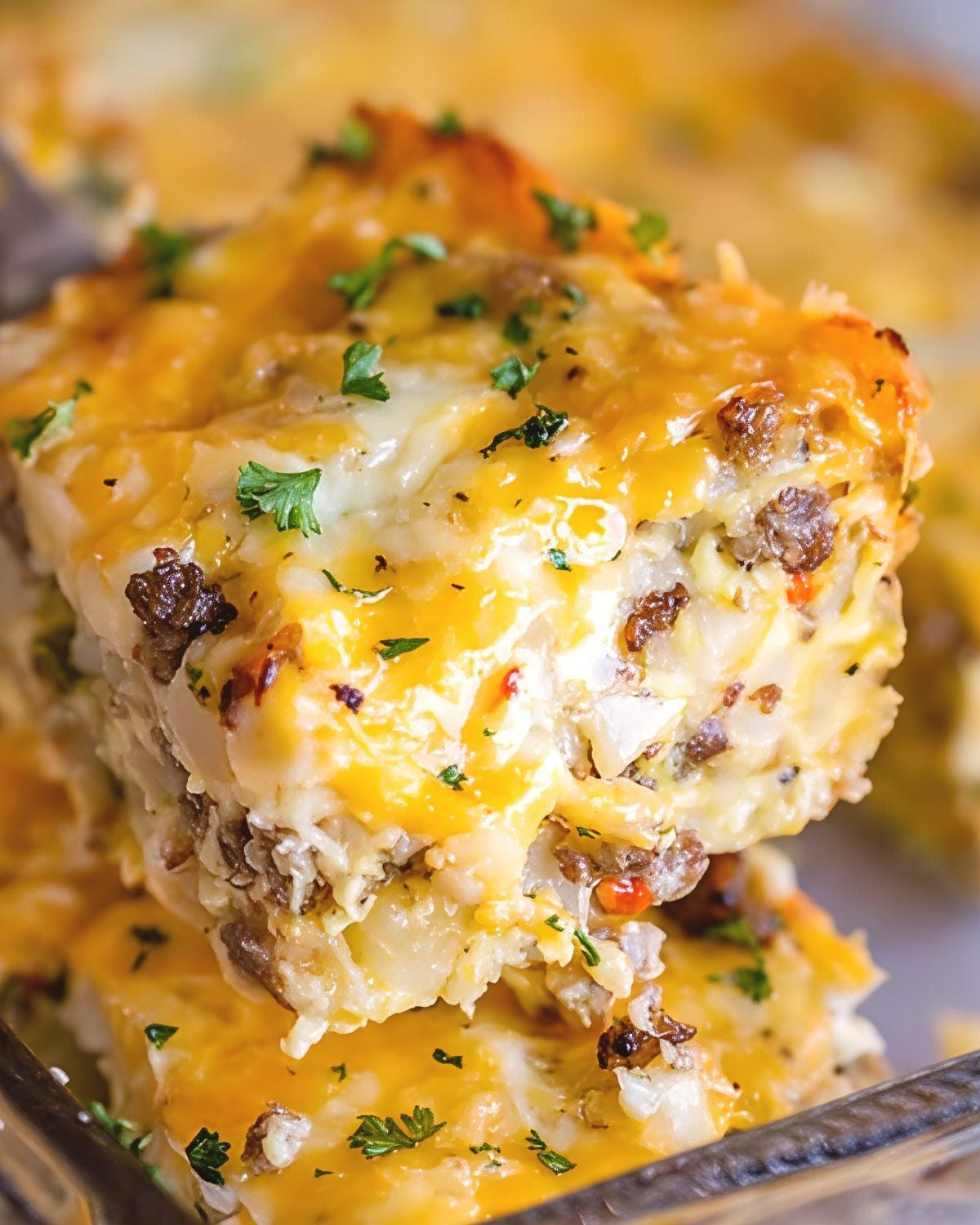 A serving of cheesy sausage breakfast casserole garnished with fresh parsley as easy Thanksgiving breakfast ideas.