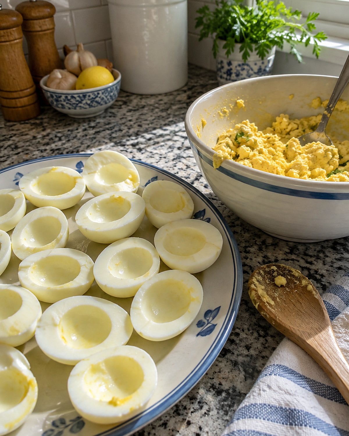 Egg whites and a bowl of mashed yolk filling sit on a kitchen counter, ready to be filled.
