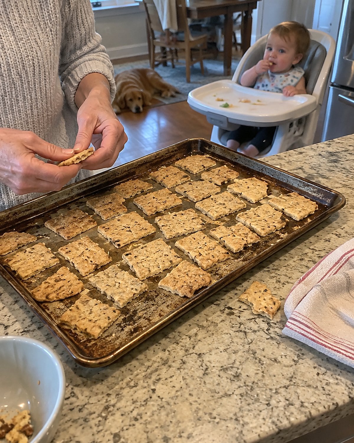 Rough homemade crackers cool on a tray beside a grandchild’s high chair.