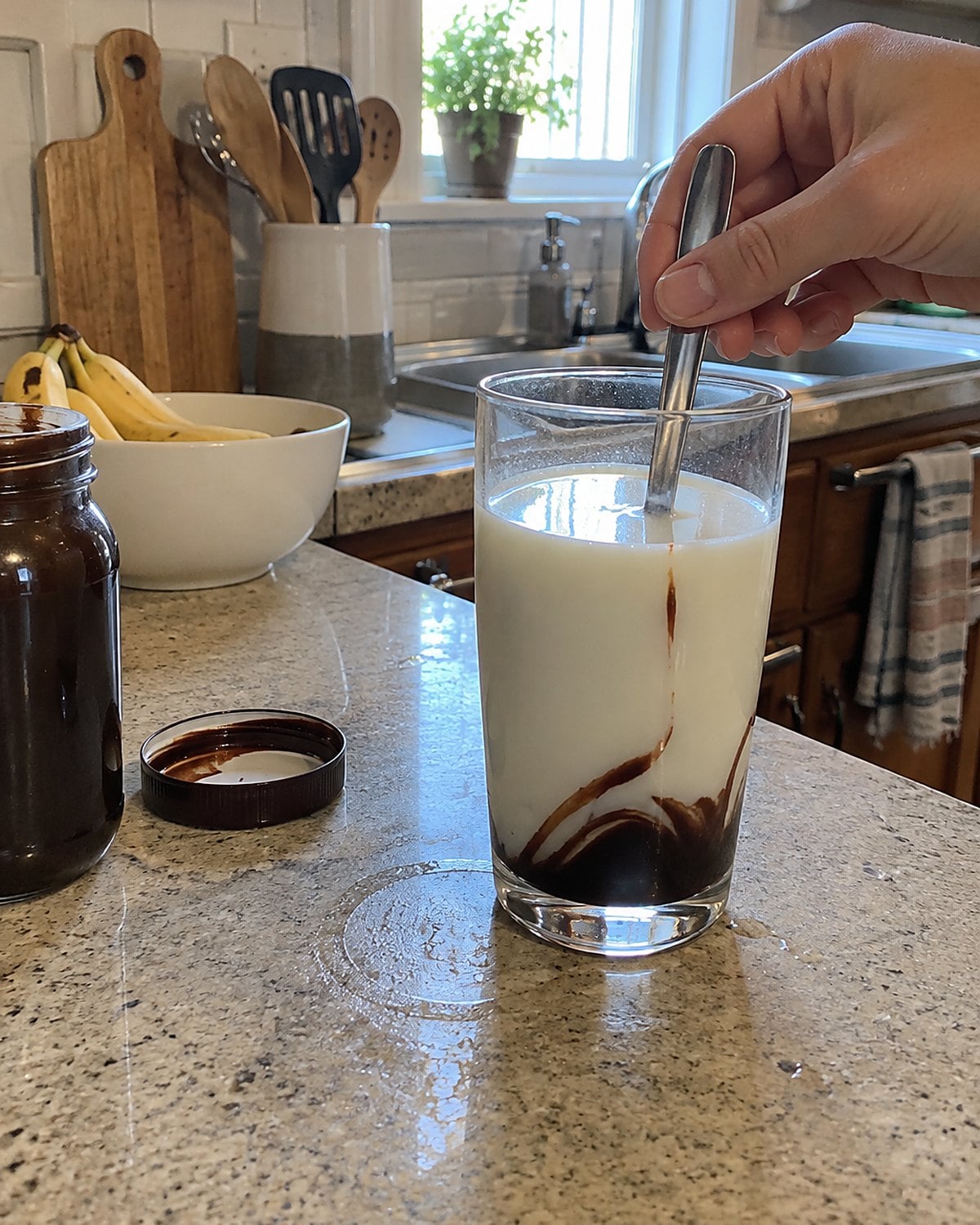 A dark streak of chocolate syrup at the bottom of a glass of milk on the counter.