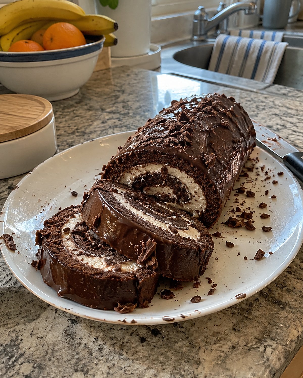 A sliced chocolate snack roll showing its spiral on a chipped plate.