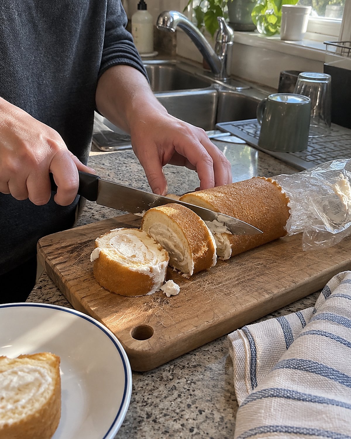 A sliced packaged snack cake with cream filling on a cutting board beside the sink.