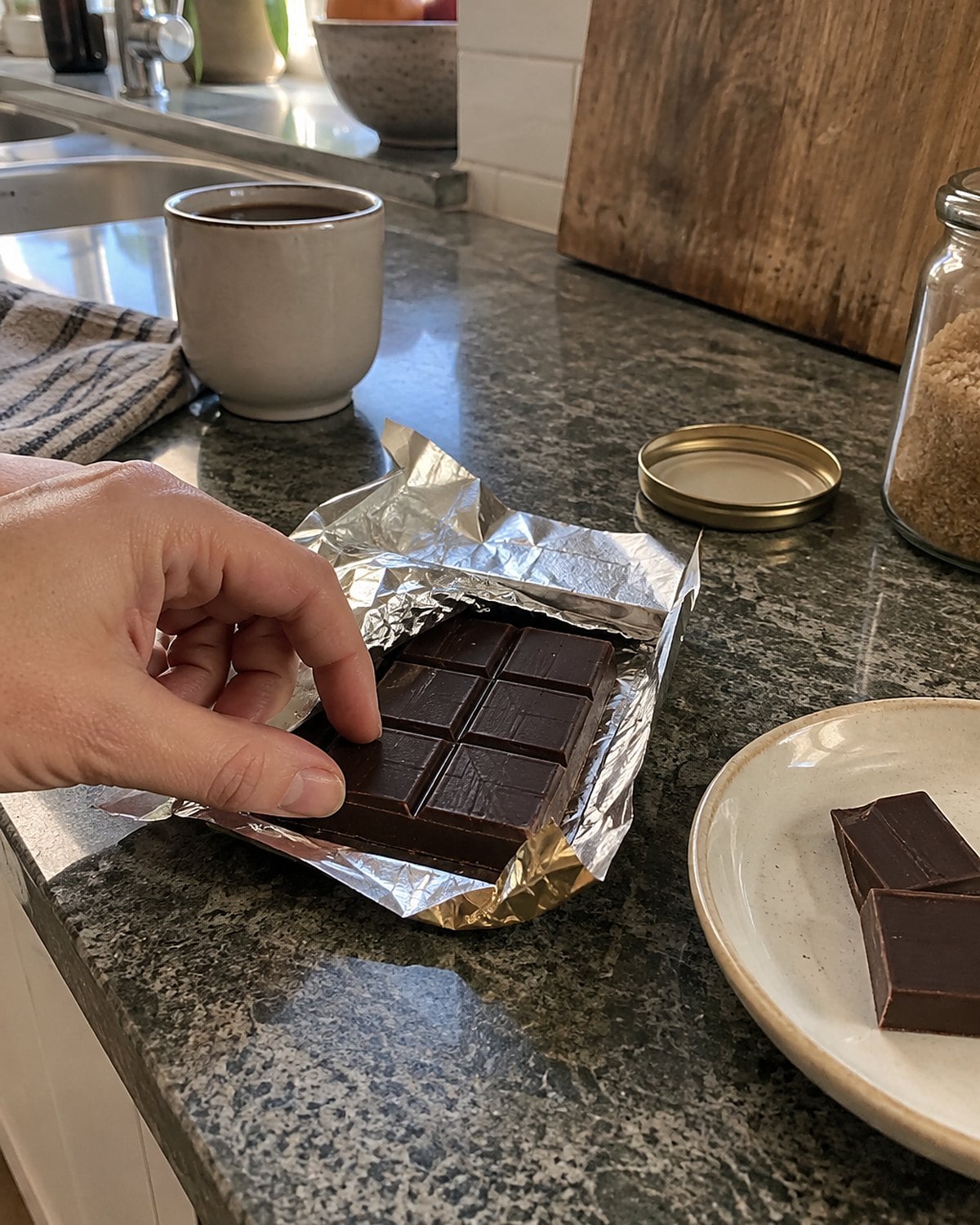 A partly unwrapped chocolate bar resting on a kitchen counter.