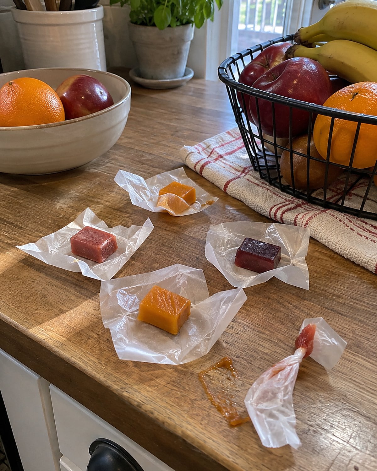 Fruit chews in opened wrappers near the checkout basket at a market stall.