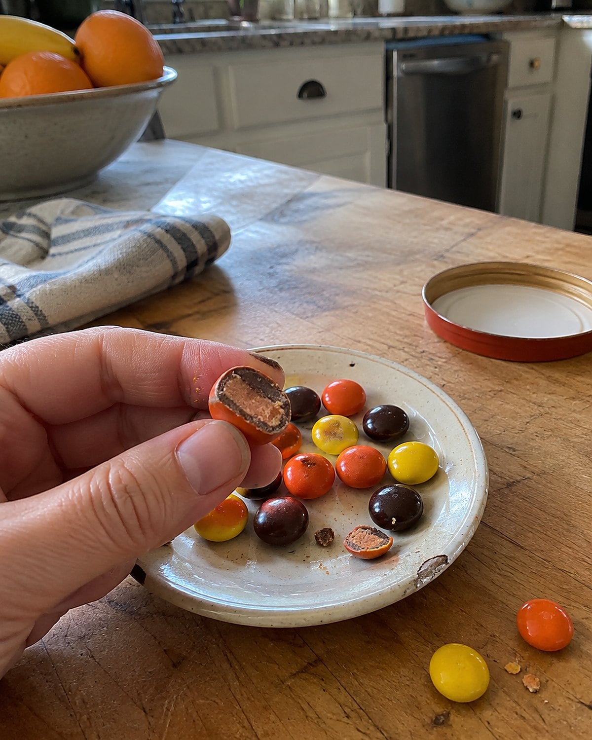 A few candy-coated peanut-butter pieces, one broken open, on a plate.