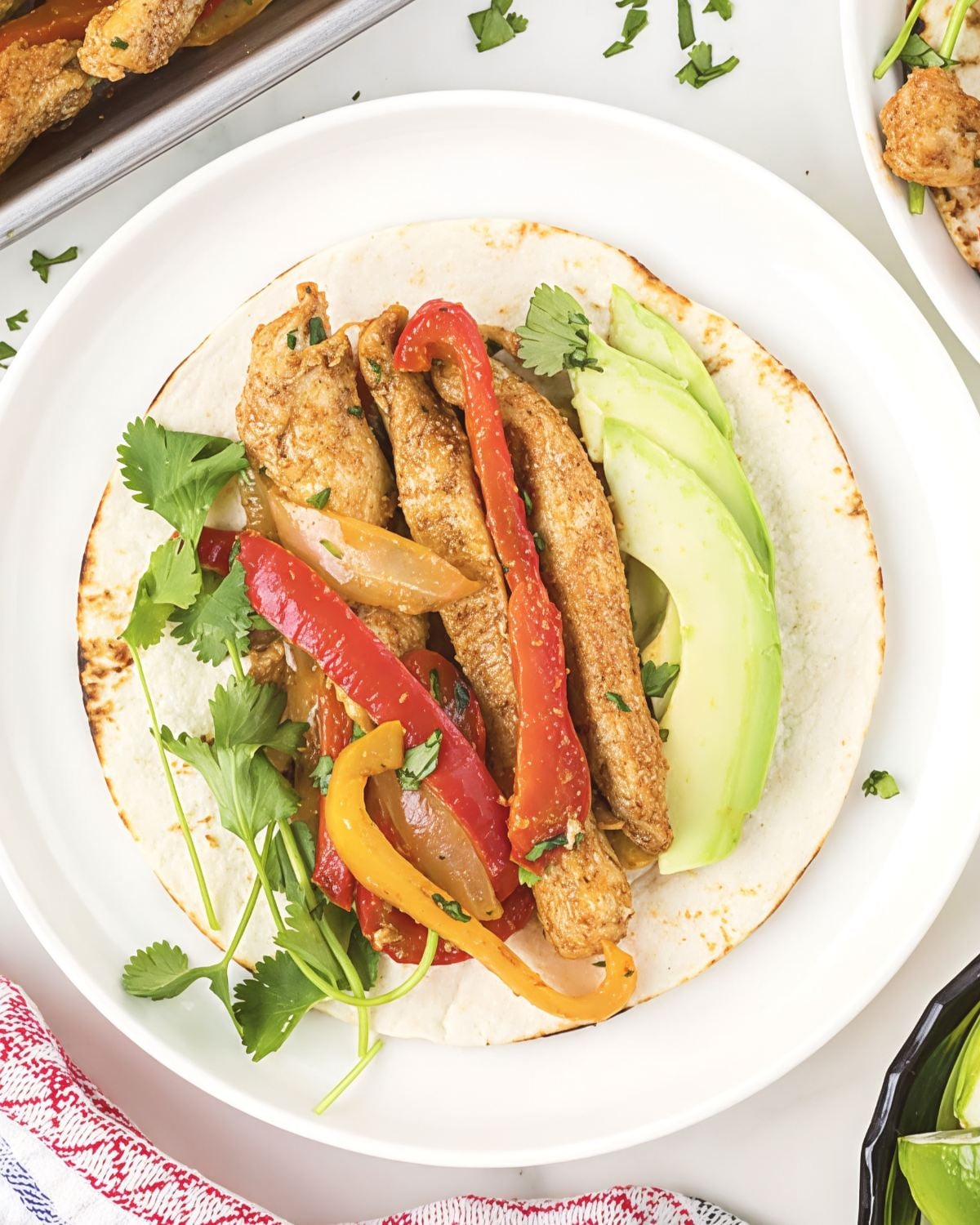 Top-down view of a low-carb fajita wrap filled with tender Sheet Pan Chicken Fajitas strips, sautรฉed onions, colorful bell peppers, and sliced avocado, featured as a delicious high protein low carb recipes dinner.