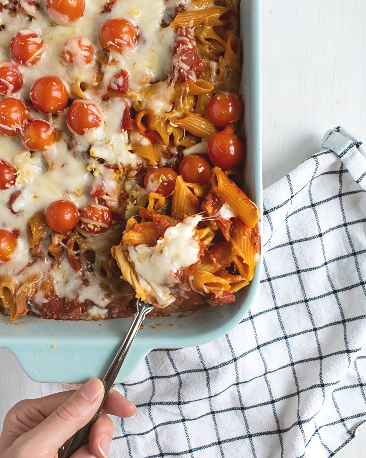 Sheet pan tomato pasta dump and bake casserole with cherry tomatoes and melted cheese in a blue baking dish
