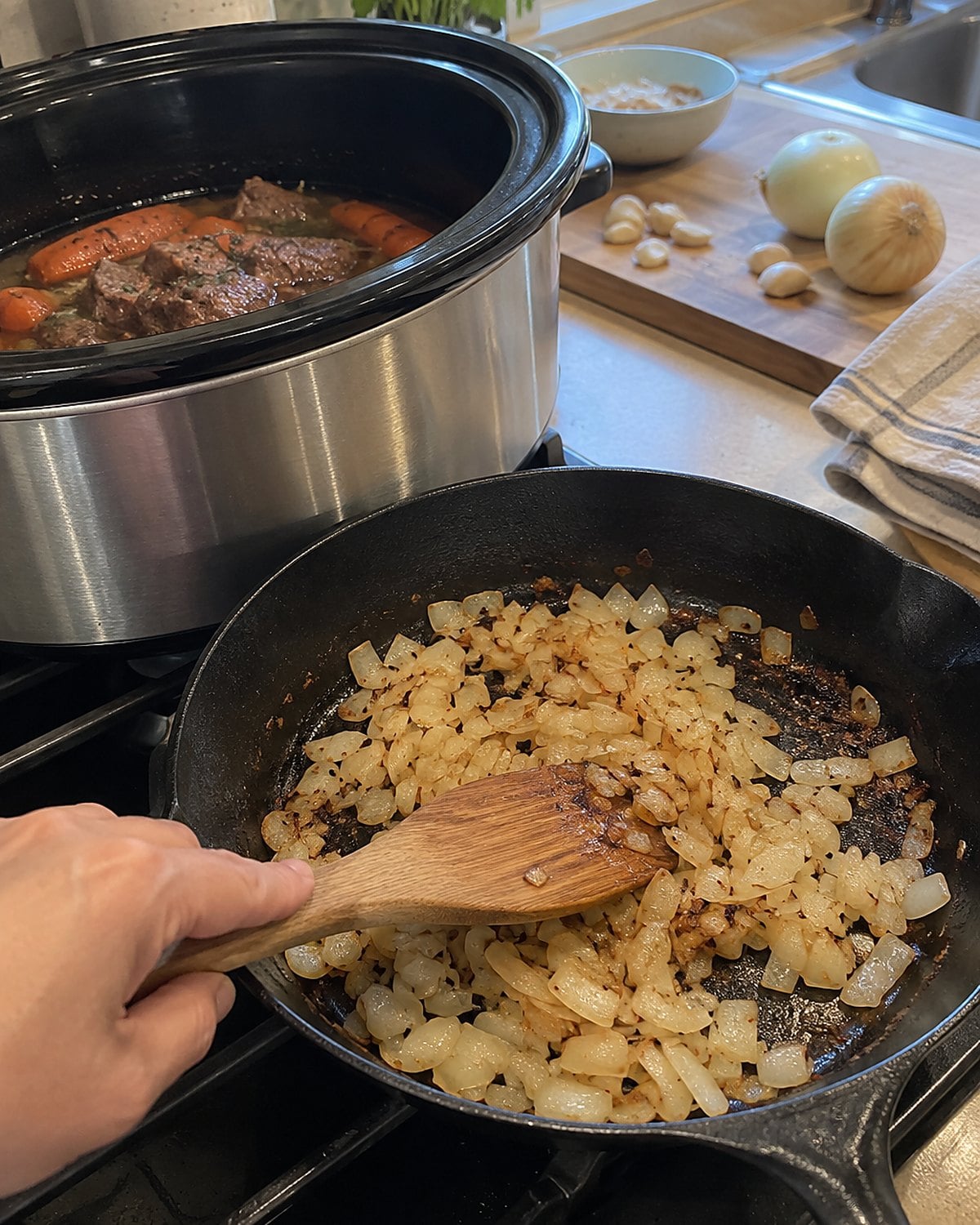 Onions browning in a worn skillet beside an open slow cooker.