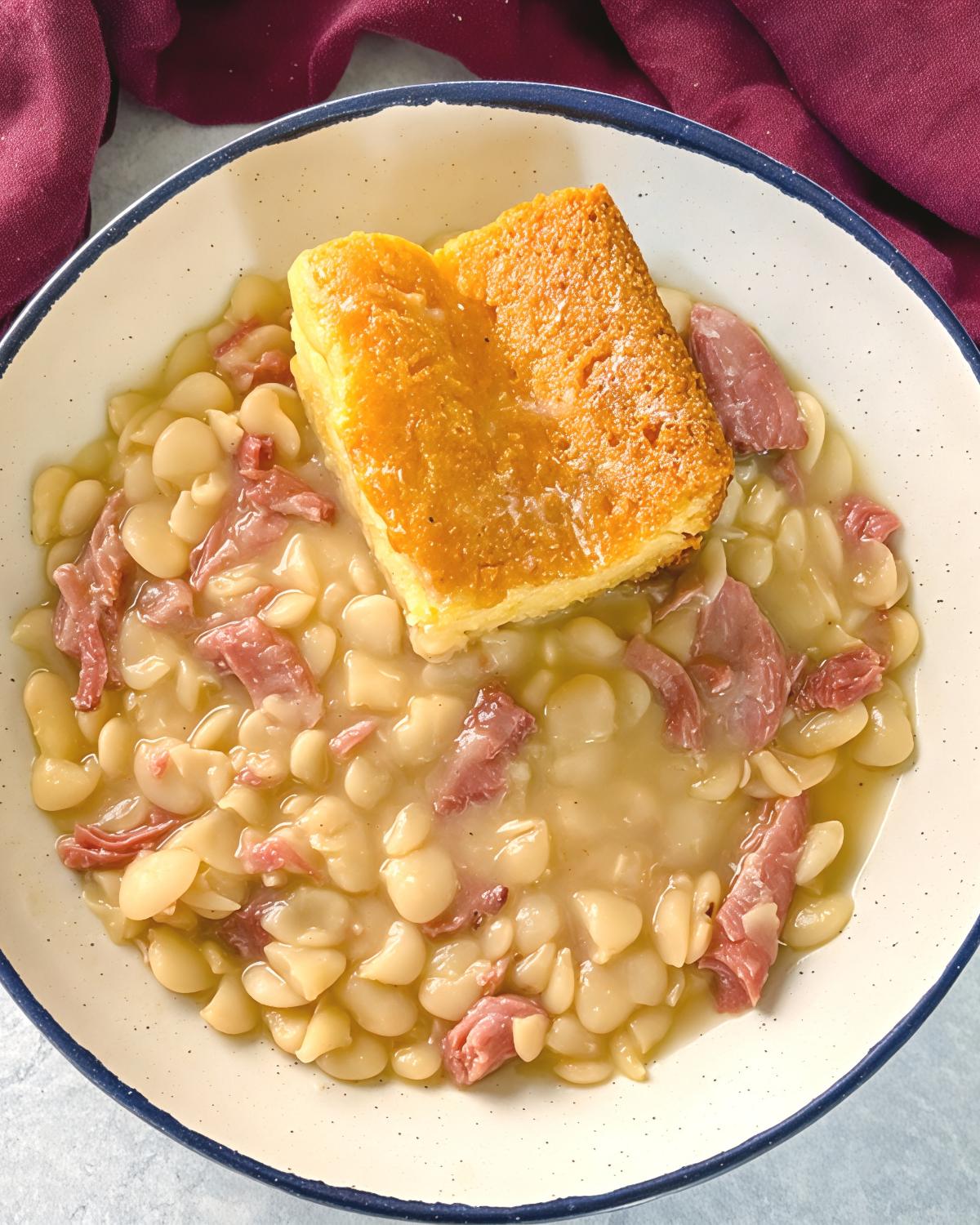 Southern butter beans cooked with smoked ham and topped with a square of golden cornbread as a traditional Thanksgiving side dish