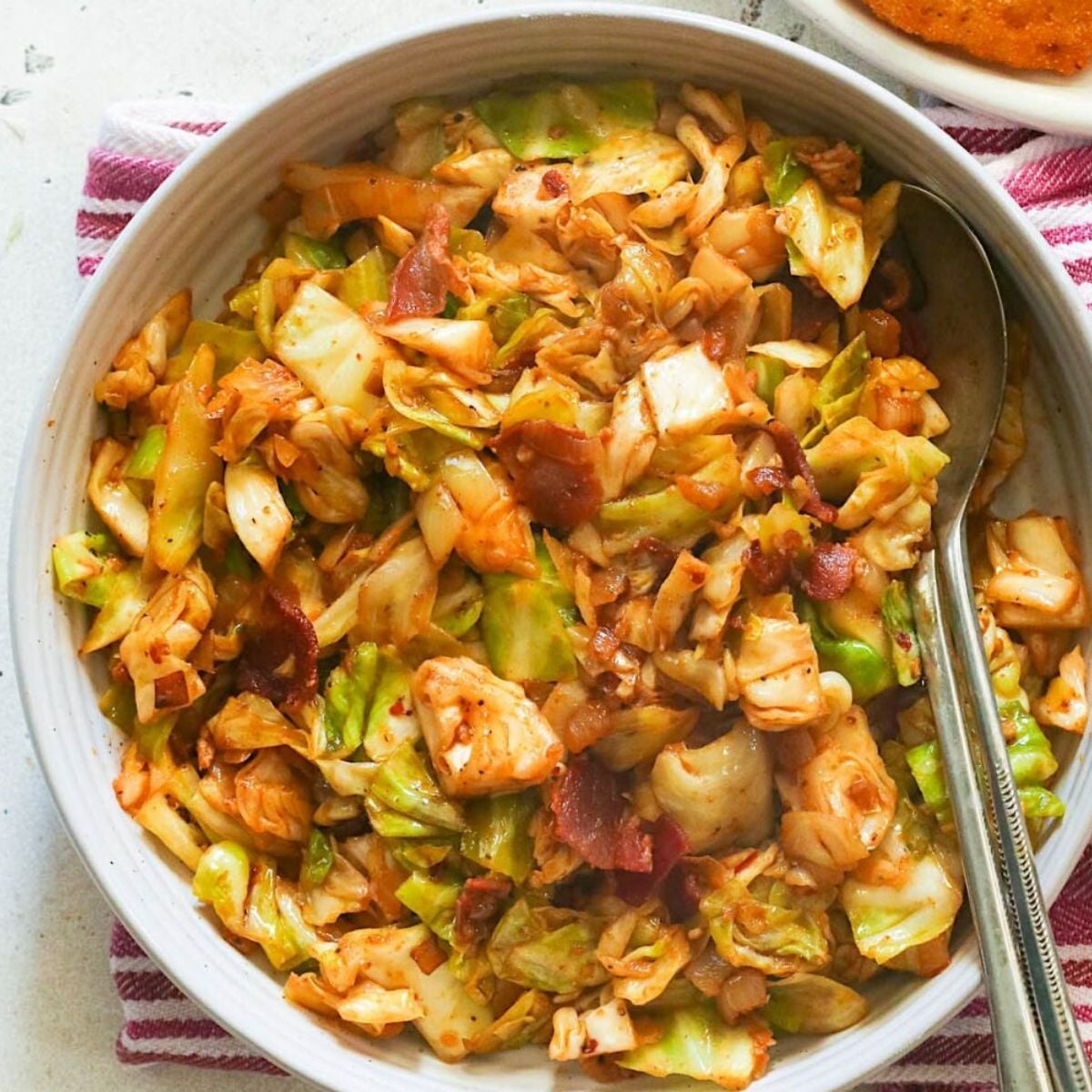 Southern fried cabbage cooked with bacon and seasonings in a white bowl as a traditional Thanksgiving side dish.
