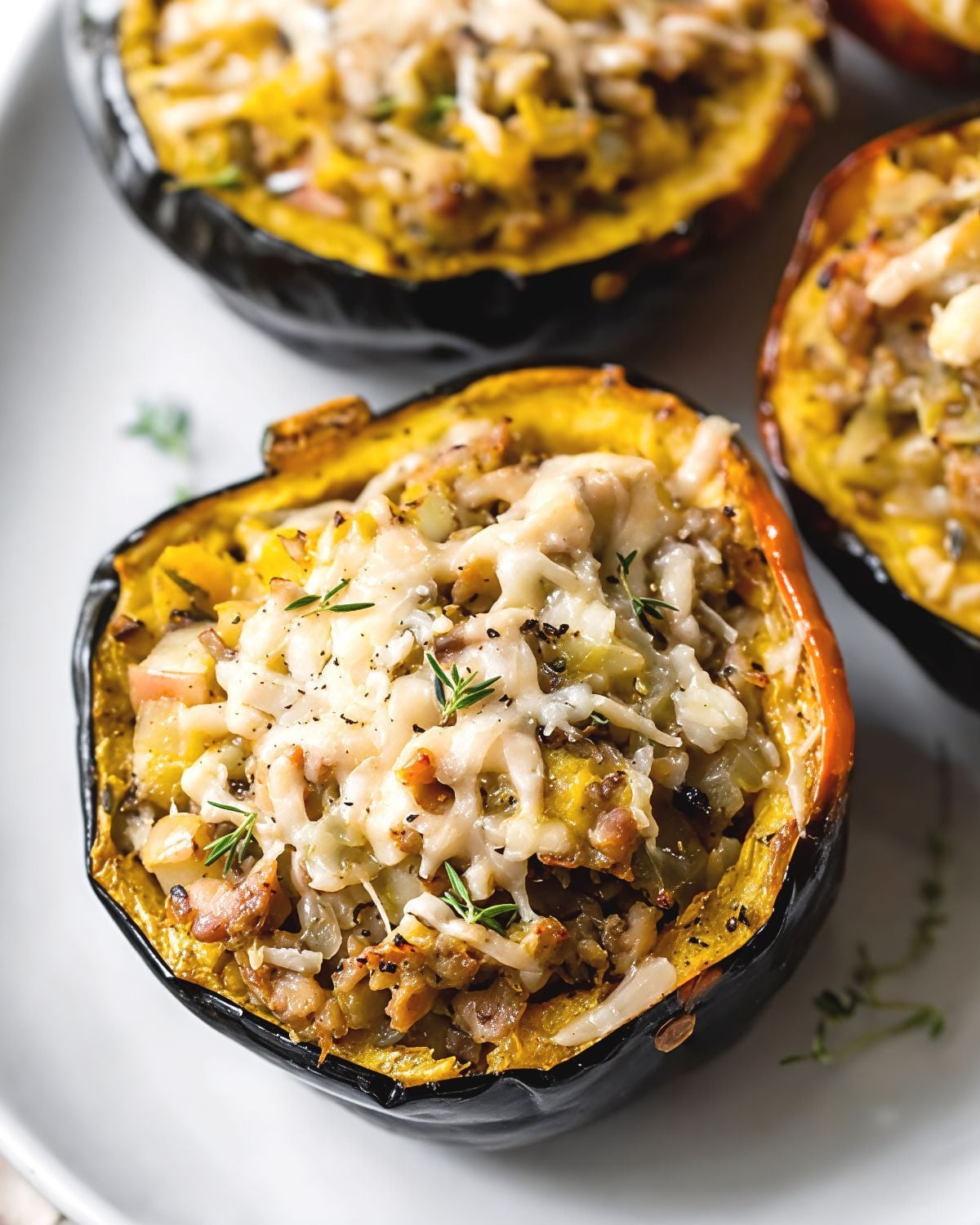 Roasted acorn squash halves stuffed with sausage and melted cheese, garnished with fresh herbs as one of the best gluten-free Thanksgiving side dishes.