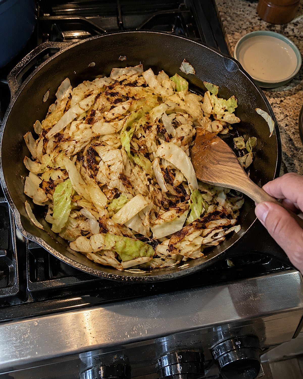 Sliced cabbage browning in a skillet on a back burner.