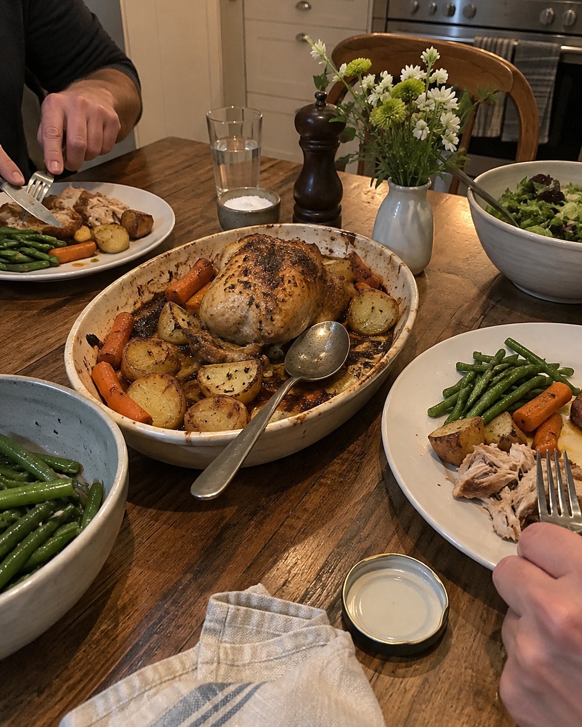 Two place settings and a small roast platter on a home dining table.