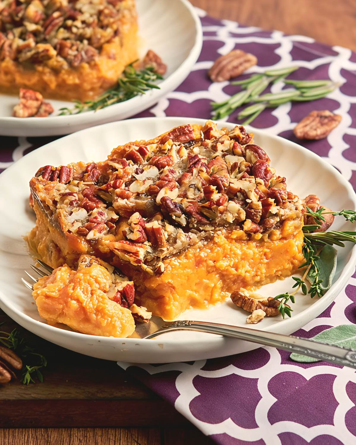 Sweet potato casserole with a crunchy pecan topping served on a white plate as a classic Southern Thanksgiving side dish.