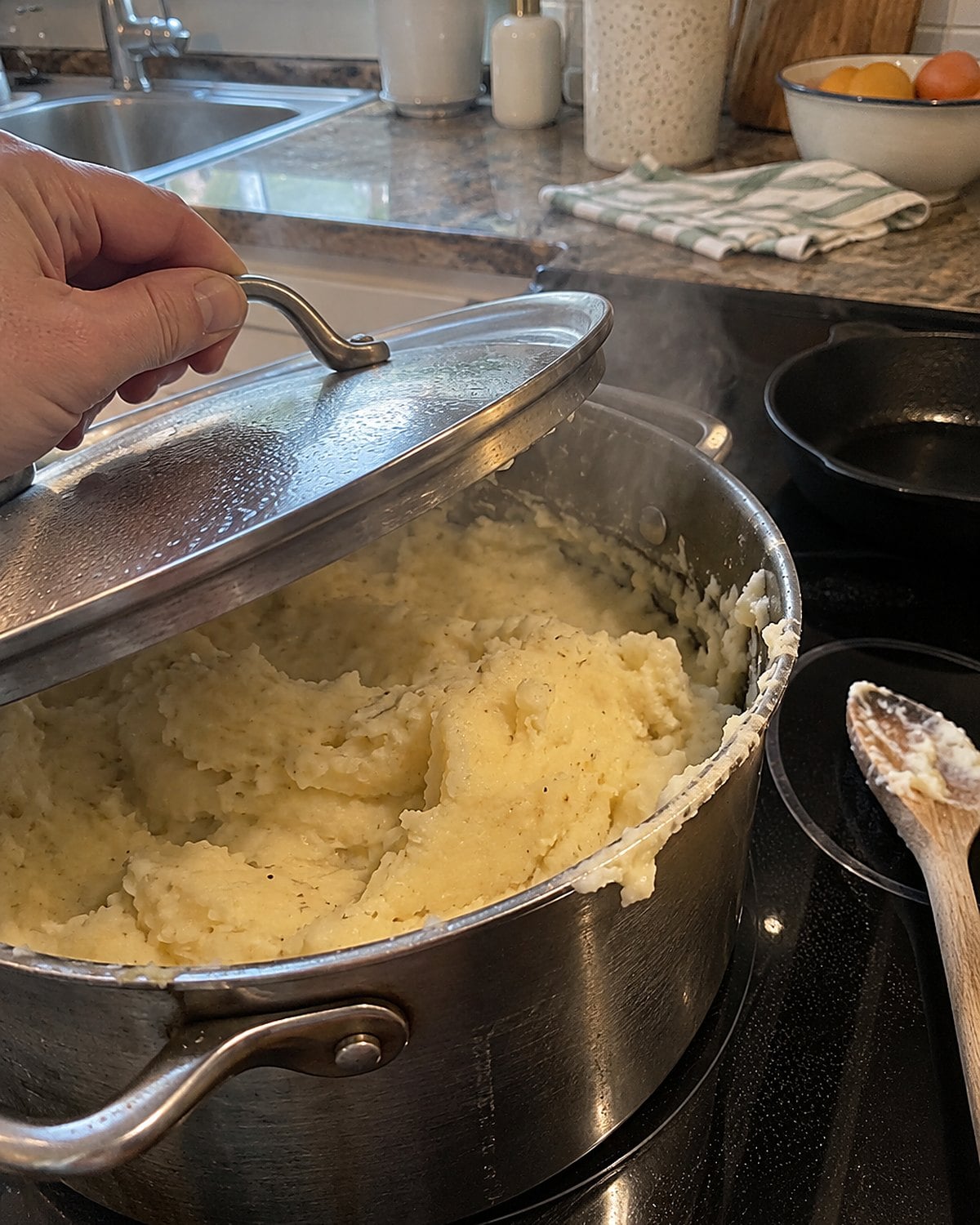 A heavy pot of mashed potatoes on a turned-off stove, its lid set askew.