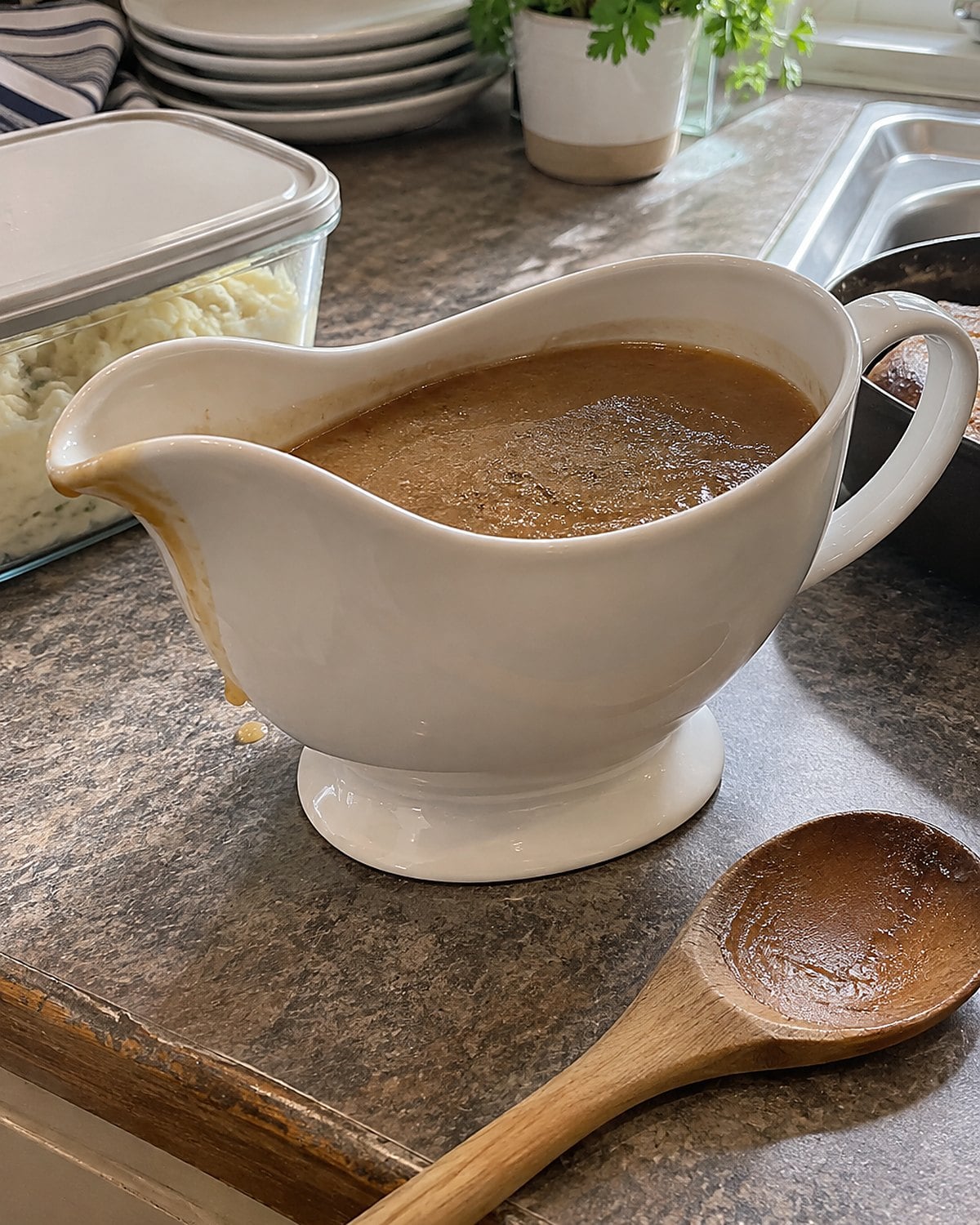 A gravy boat with a skin across the surface beside a clean storage container.