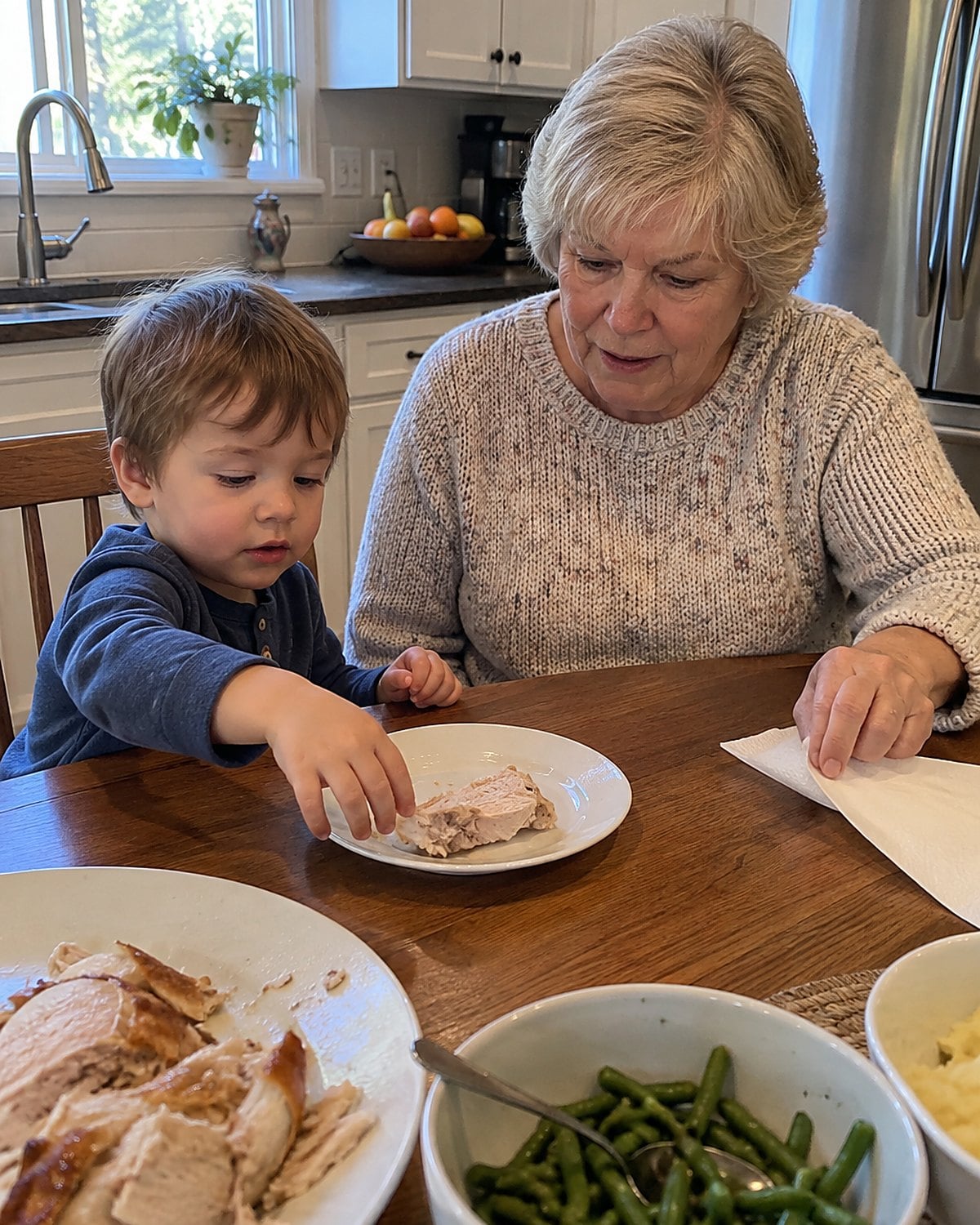 A grandchildโs hand beside a half-eaten piece of turkey on a small plate.