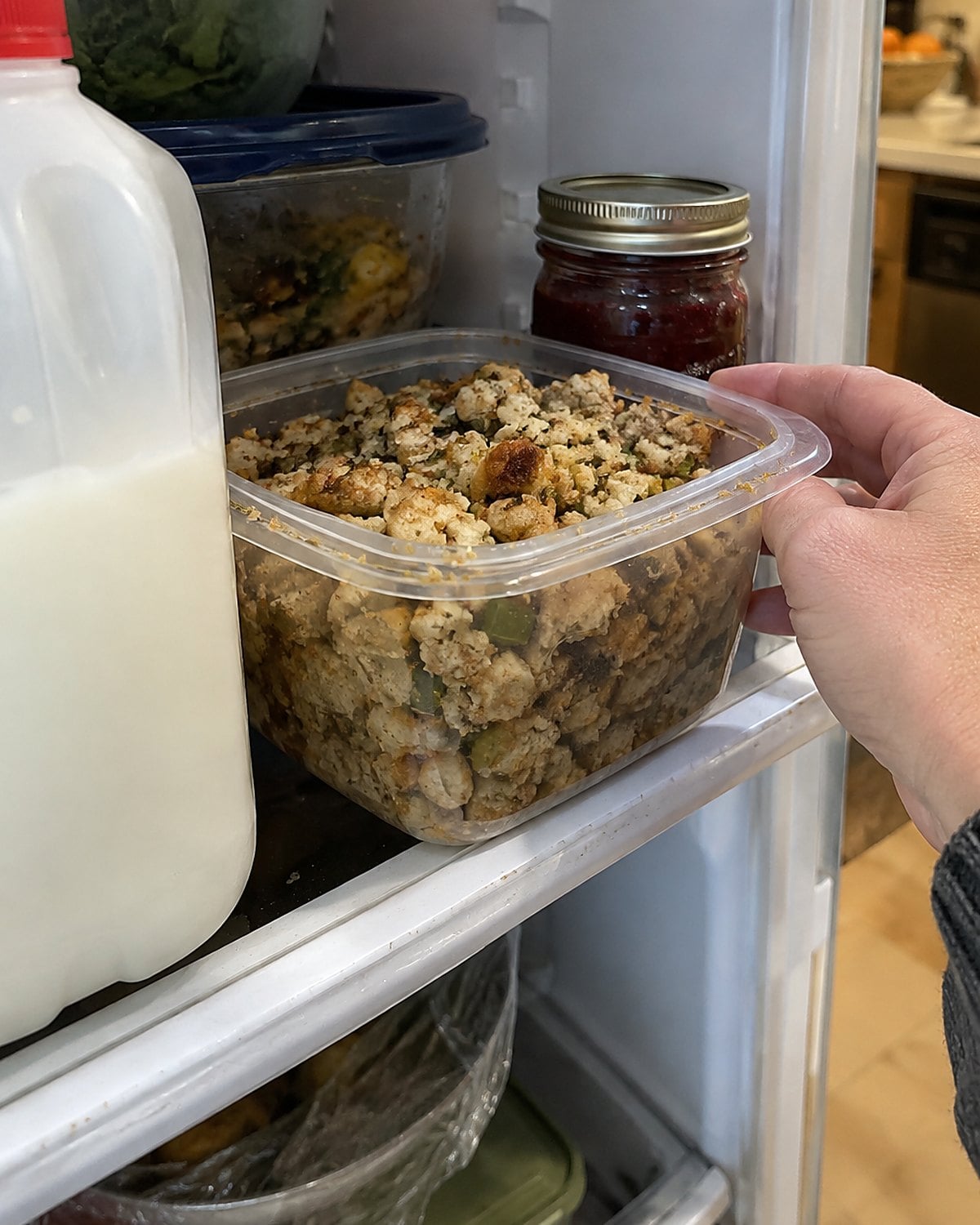 A container of stuffing tucked behind milk on a Wednesday refrigerator shelf.