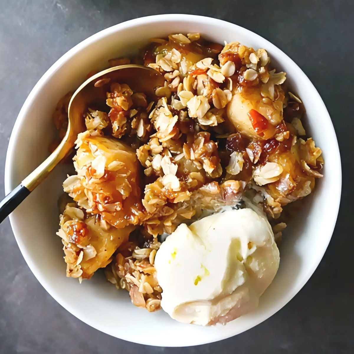 A bowl of warm Instant Pot apple crisp topped with golden oat streusel and a scoop of vanilla ice cream, ideal for easy Thanksgiving potluck desserts.