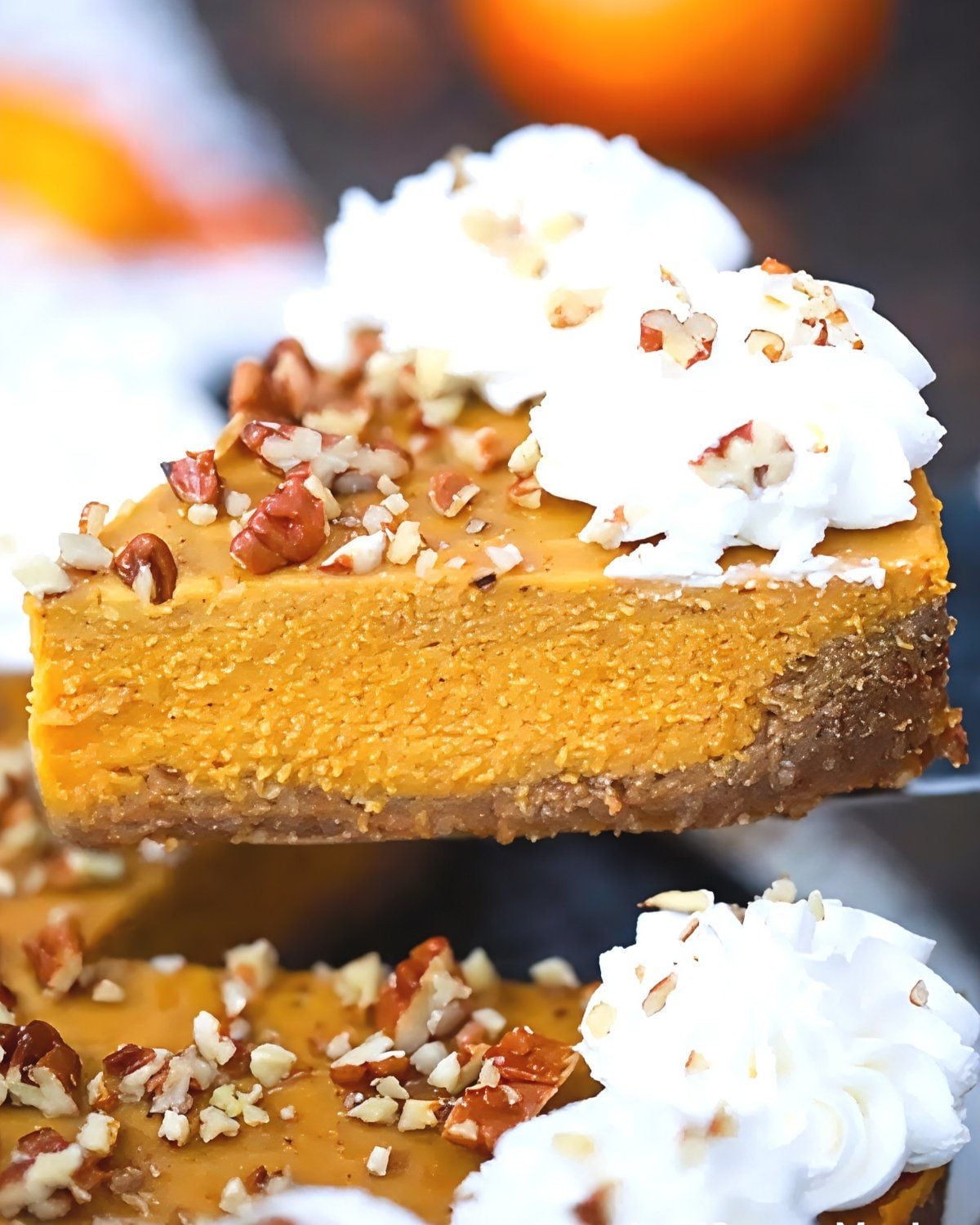 A slice of creamy Instant Pot pumpkin pie with a graham cracker crust, topped with whipped cream and chopped pecans, perfect for Thanksgiving potluck desserts.