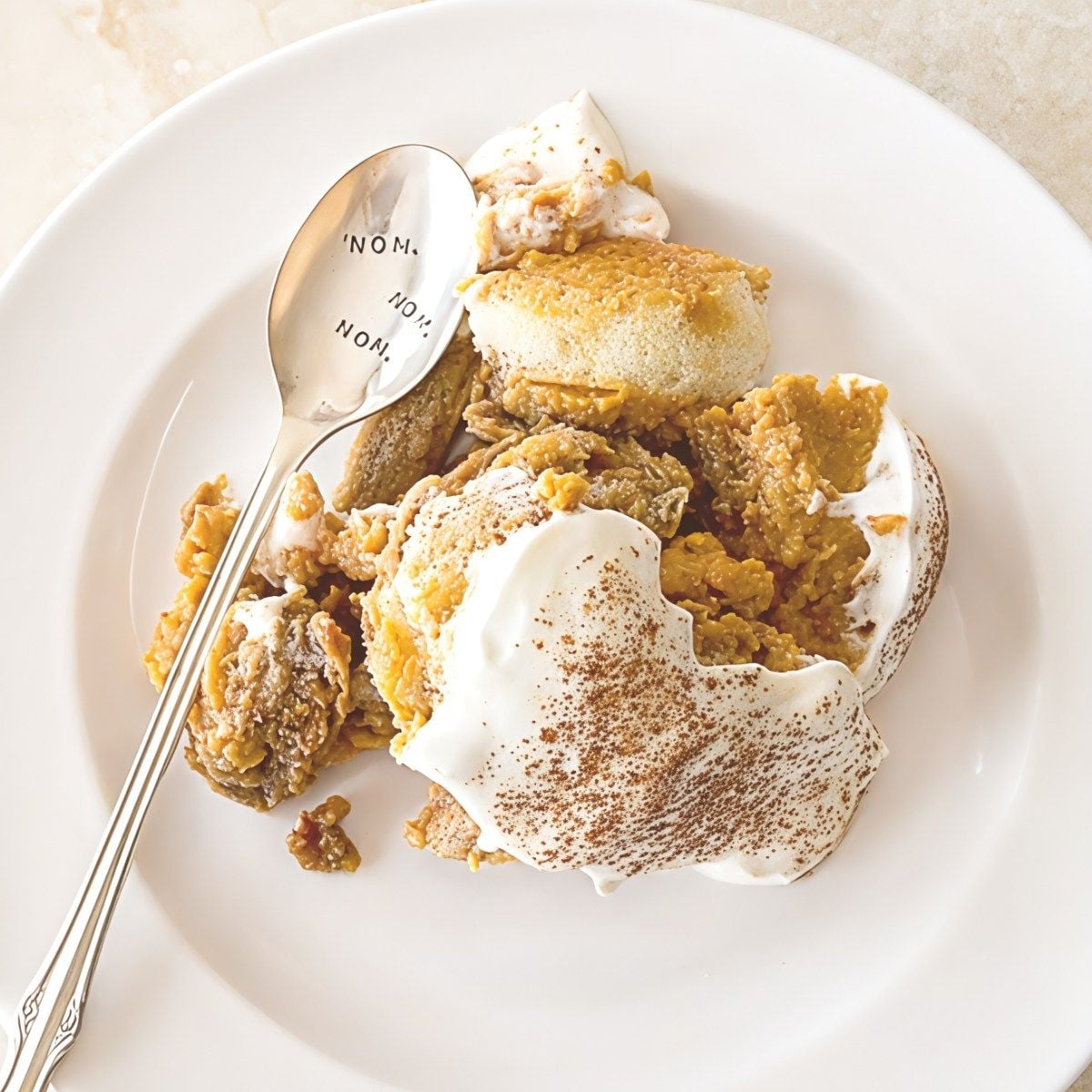 A serving of creamy pumpkin tiramisu topped with whipped mascarpone cream and dusted with cocoa powder, perfect for Thanksgiving potluck desserts.