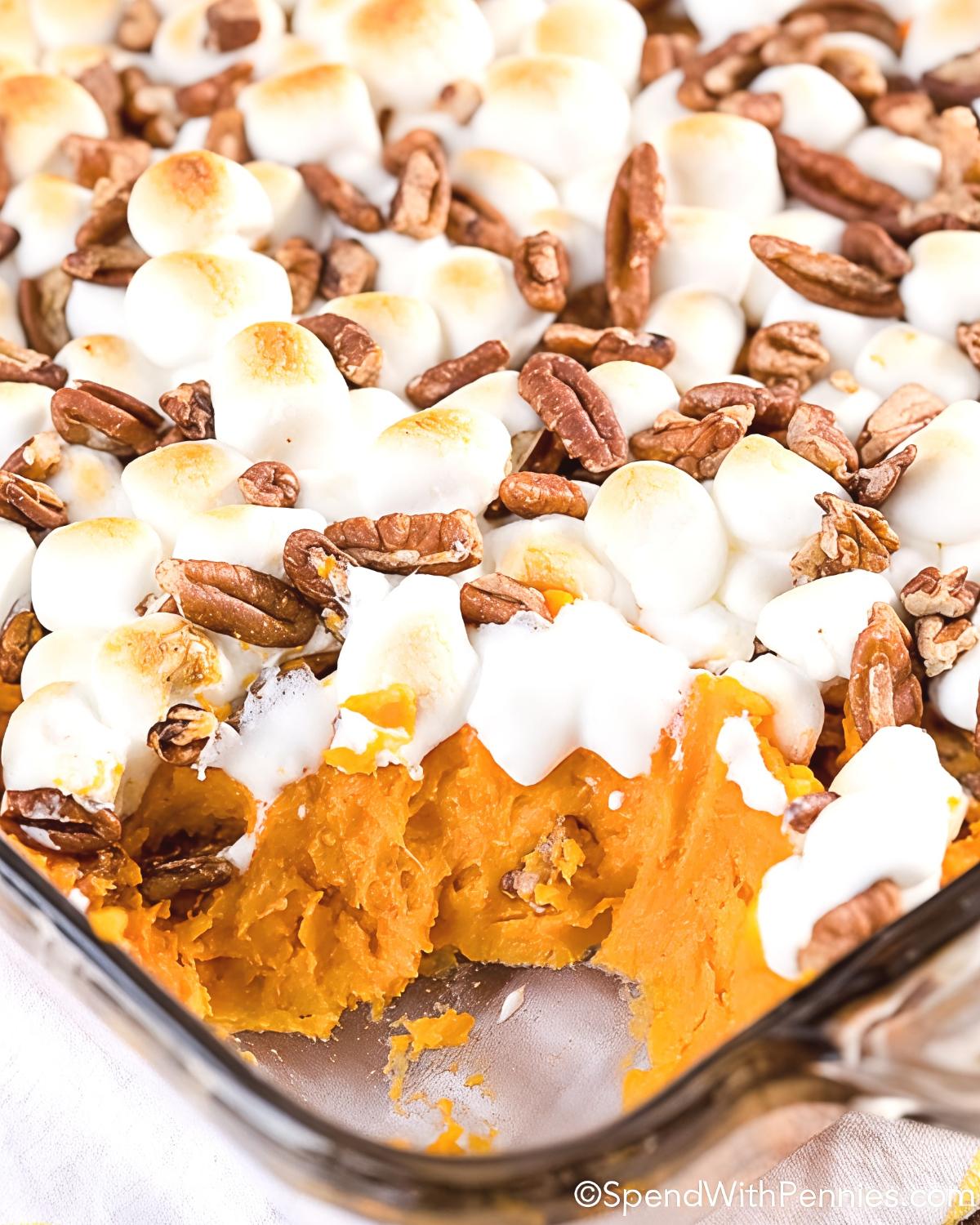 Creamy mashed sweet potato casserole topped with toasted mini marshmallows and crunchy pecans in a glass baking dish, perfect for Thanksgiving side dishes for a crowd.