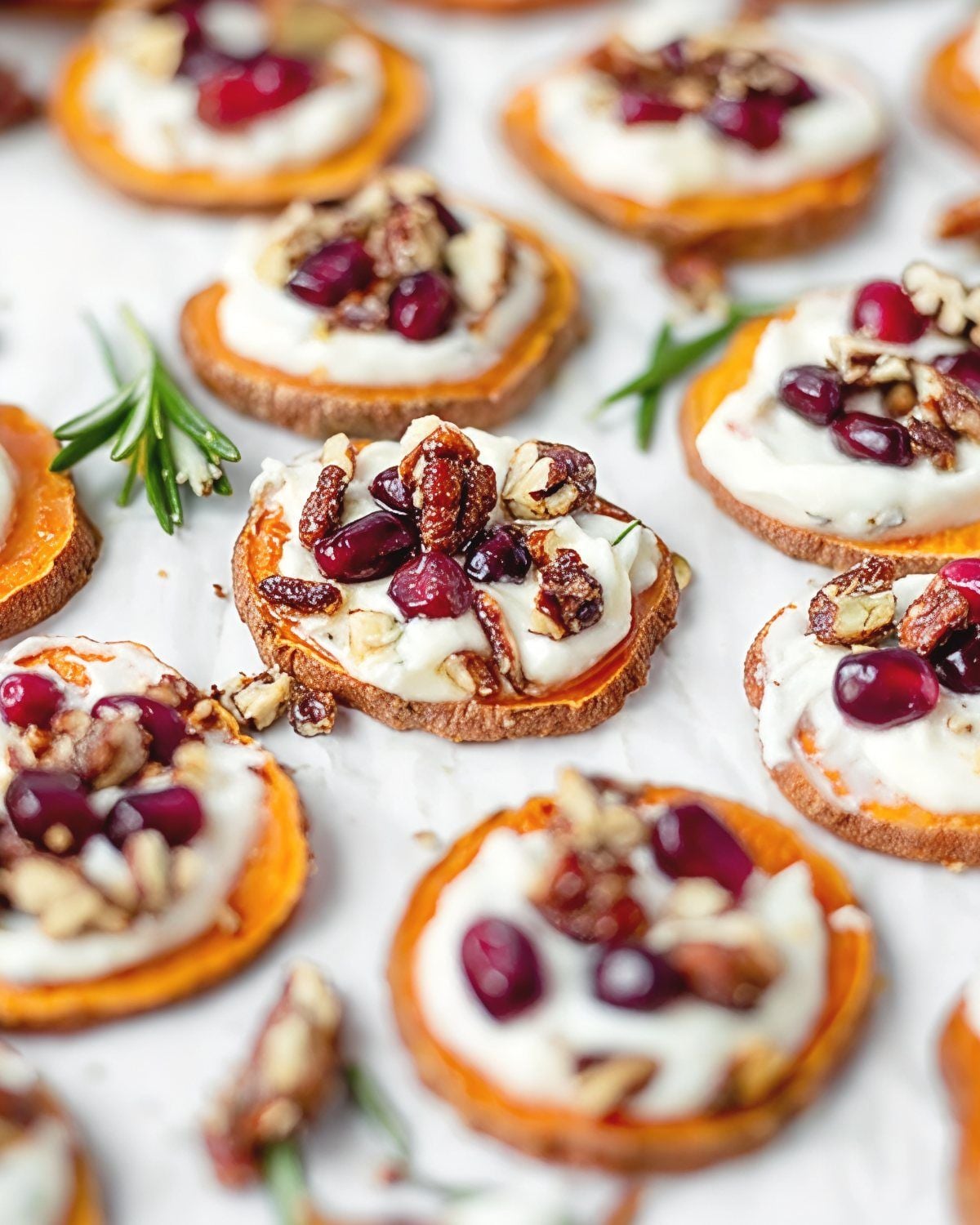 A photograph shows round, roasted sweet potato bites topped with a white, spreadable cheese, dark red cranberries, and chopped walnuts, serving as Thanksgiving Snacks Appetizers