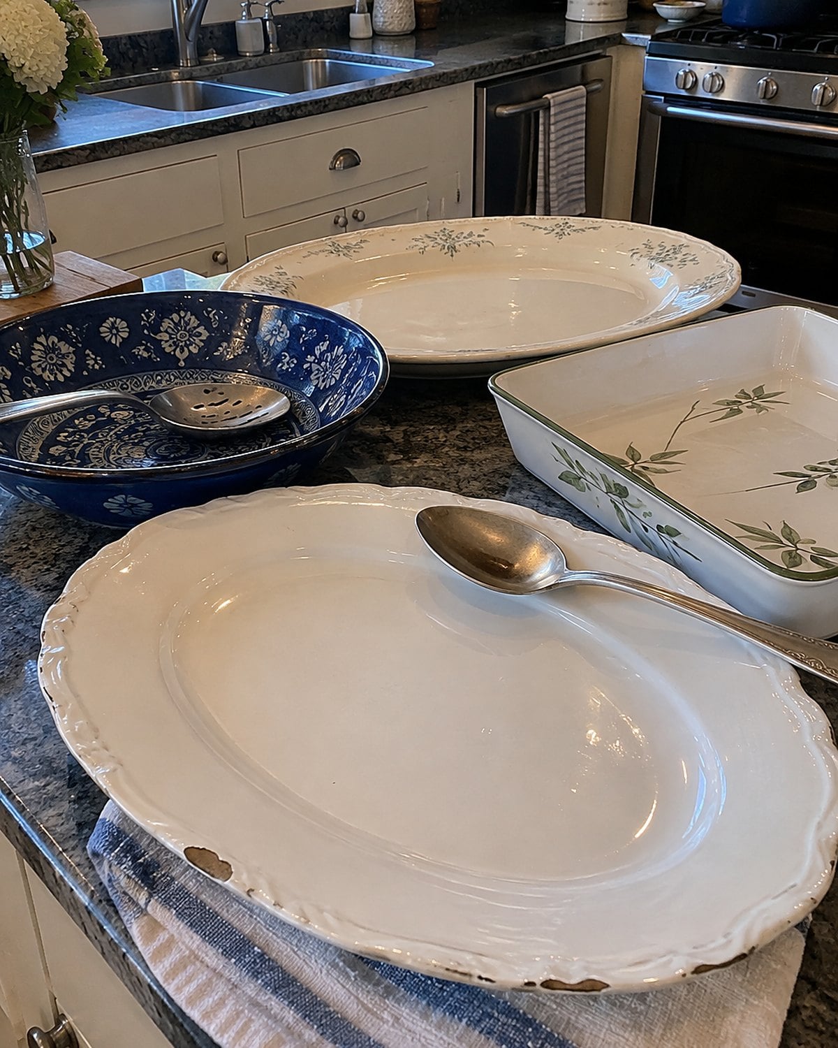 Empty serving platters sit on a side counter beside mismatched serving spoons.