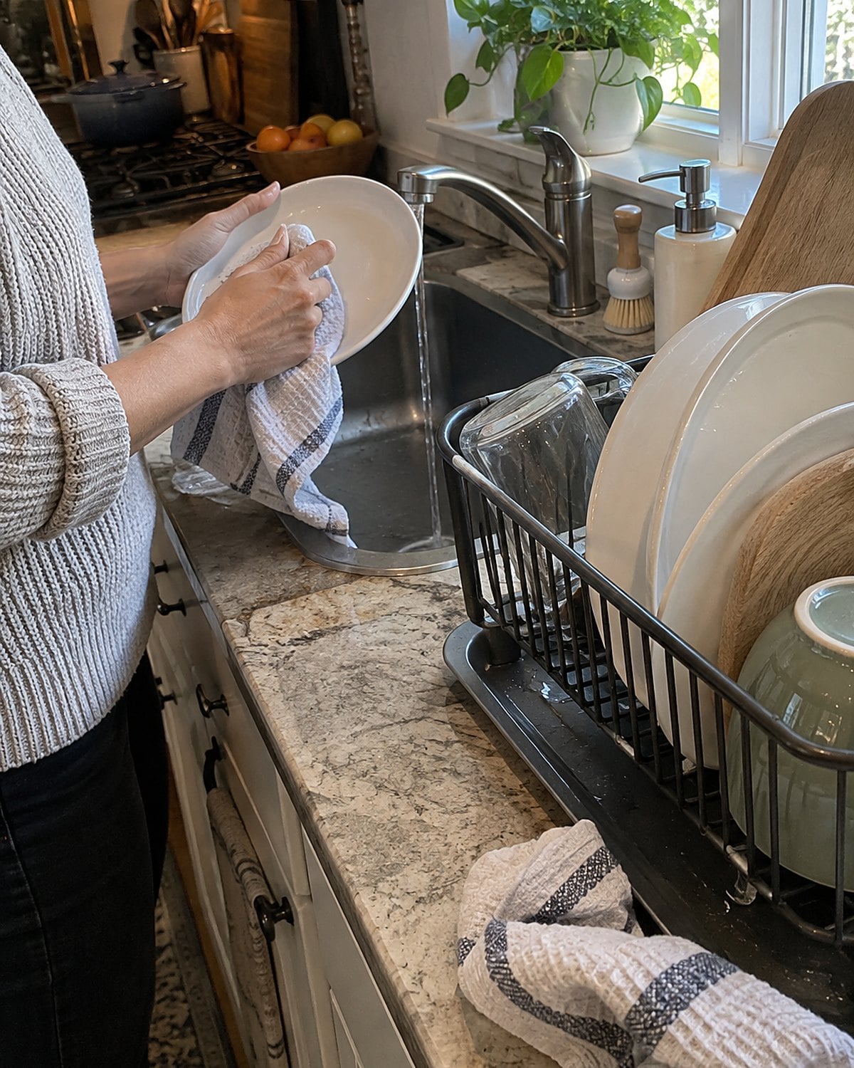Plates and a wooden cutting board dry in a dish rack beside the sink.