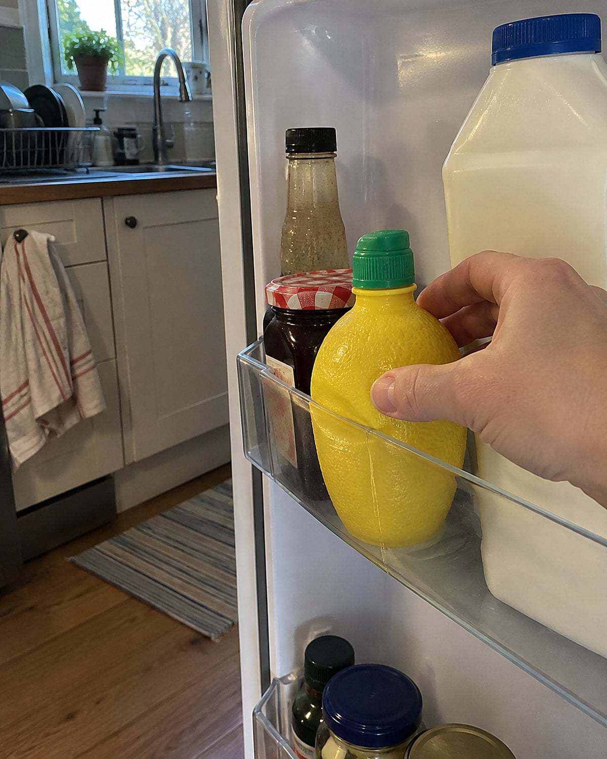 A plastic lemon-shaped juice bottle stands in a refrigerator door beside a carton of milk.