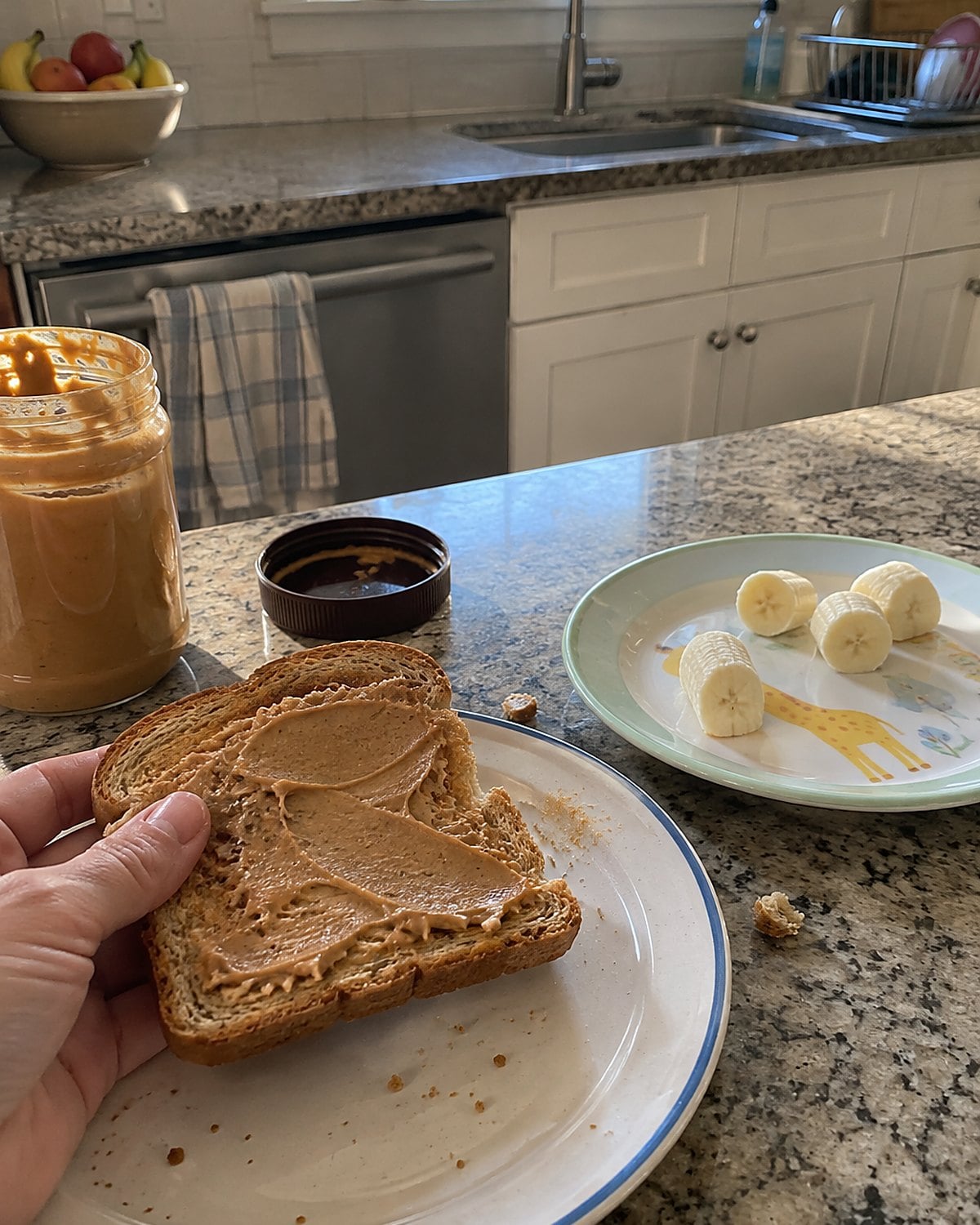 A thin smear of peanut butter on toast beside a child’s small plate.
