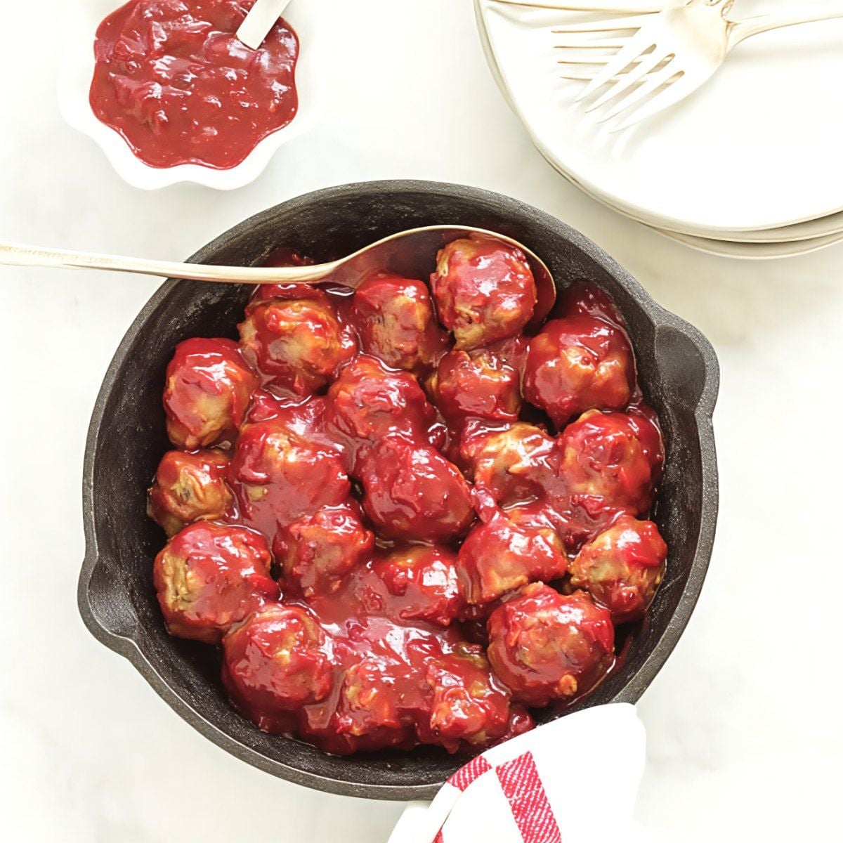 Mini turkey meatballs coated in a rich curried cranberry sauce served hot in a cast-iron skillet as a healthy, light Thanksgiving appetizer.