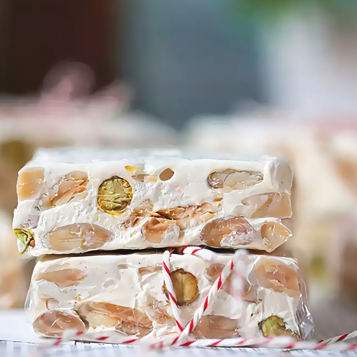 Slices of traditional Spanish turrón white nougat packed with toasted almonds and pistachios, wrapped in red-and-white string as a festive European Christmas dessert.