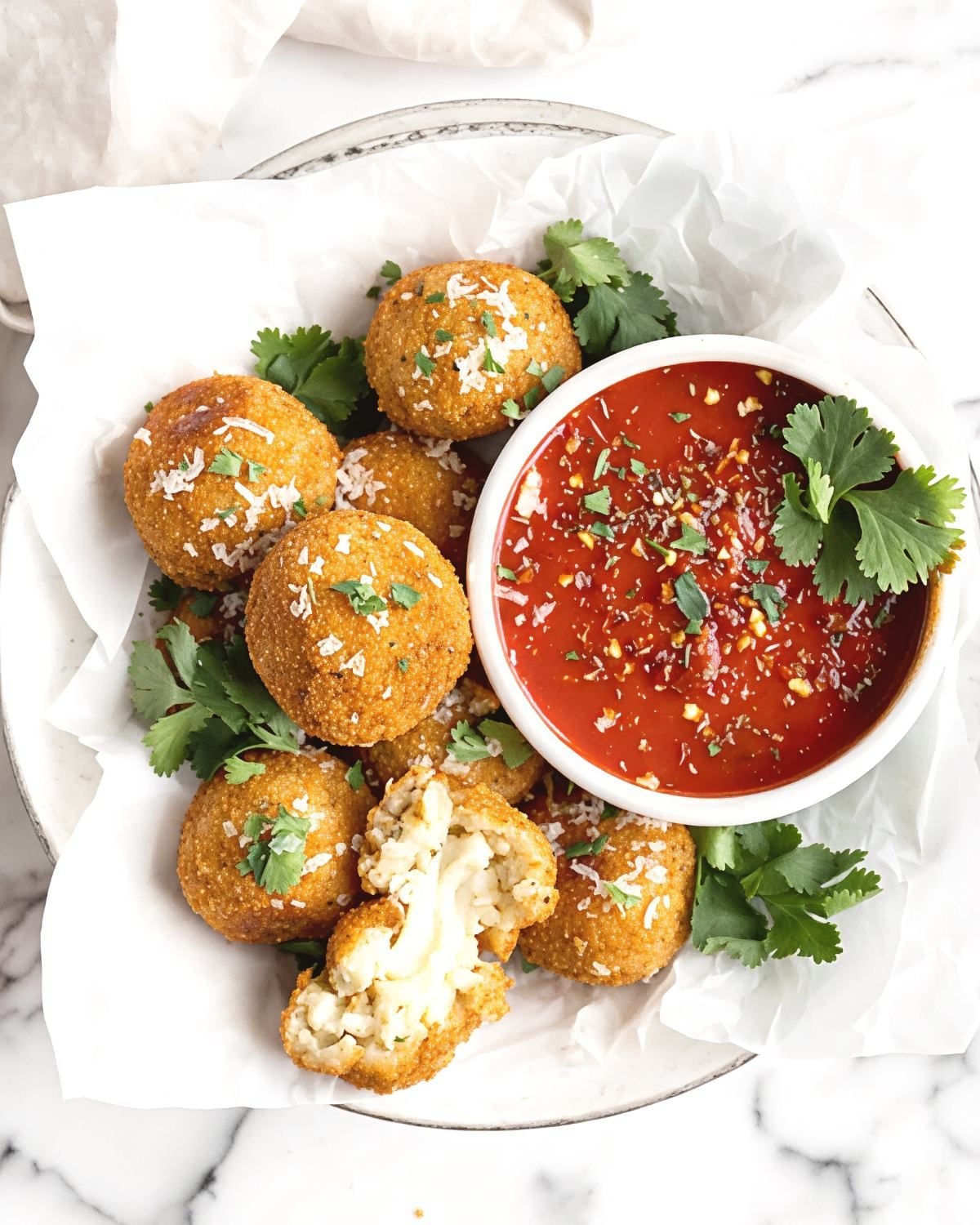 Crispy golden vegan arancini fried rice balls served with a side of marinara dip and fresh herbs, perfect for vegan Thanksgiving appetizers.