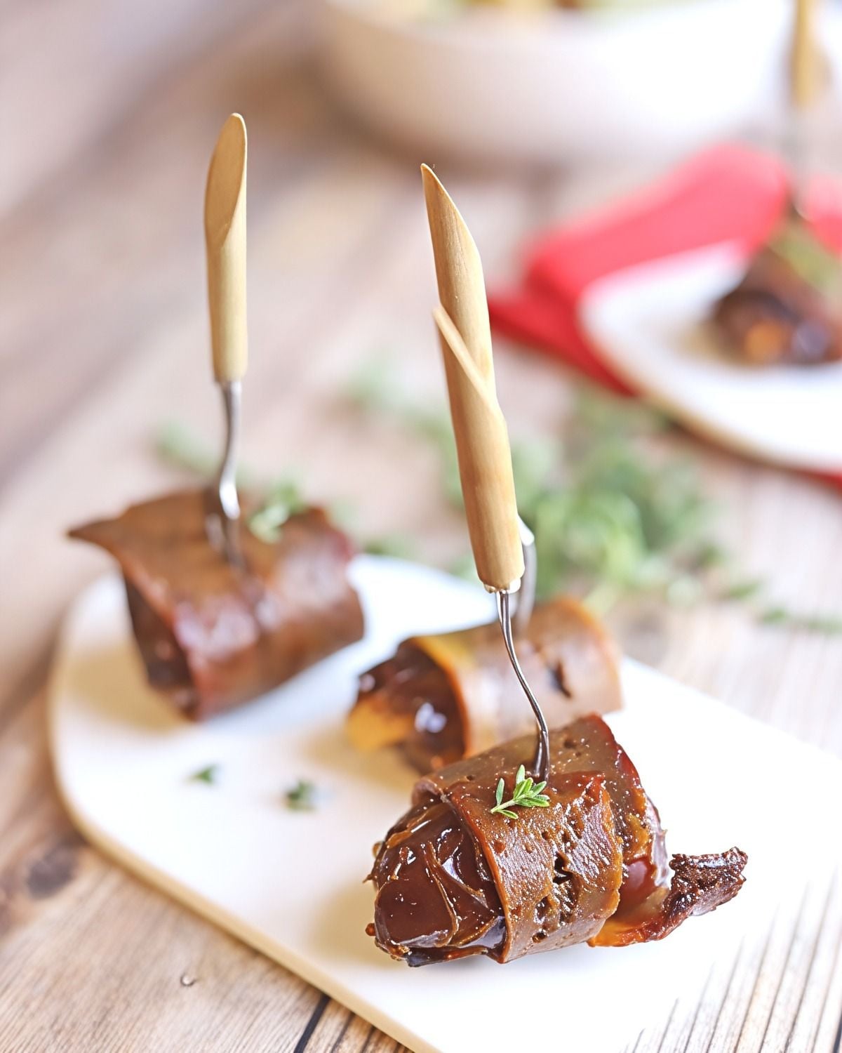 Vegan bacon-wrapped dates pierced with wooden cocktail forks, presented as one of the best vegan Thanksgiving appetizers.