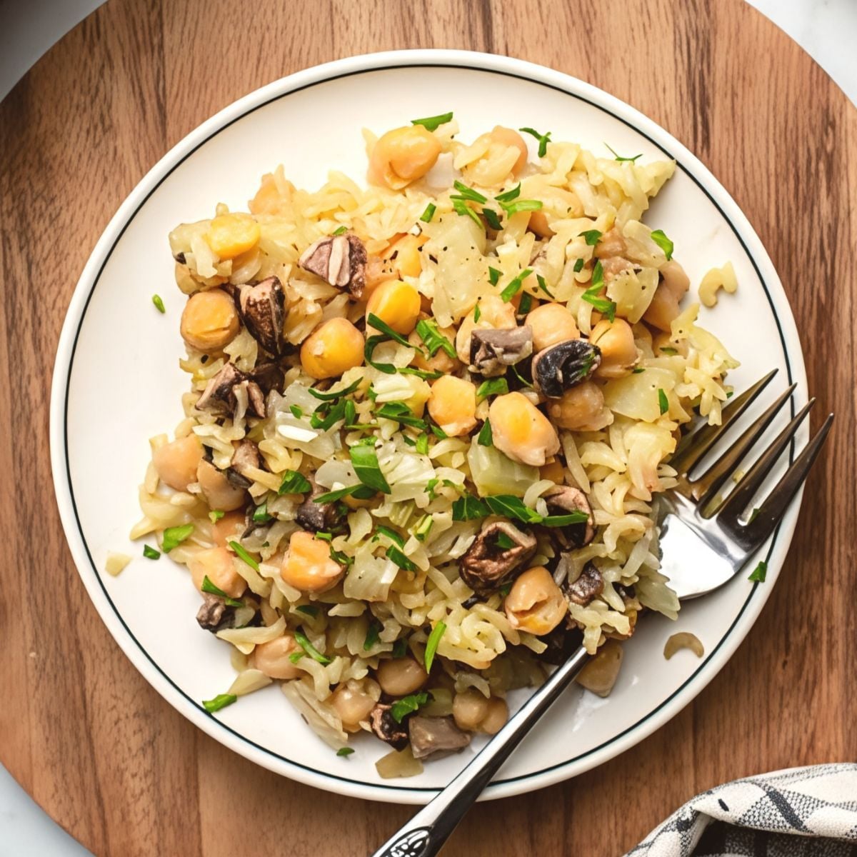 Vegan chickpea and rice casserole served on a white plate with fresh herbs and a fork.