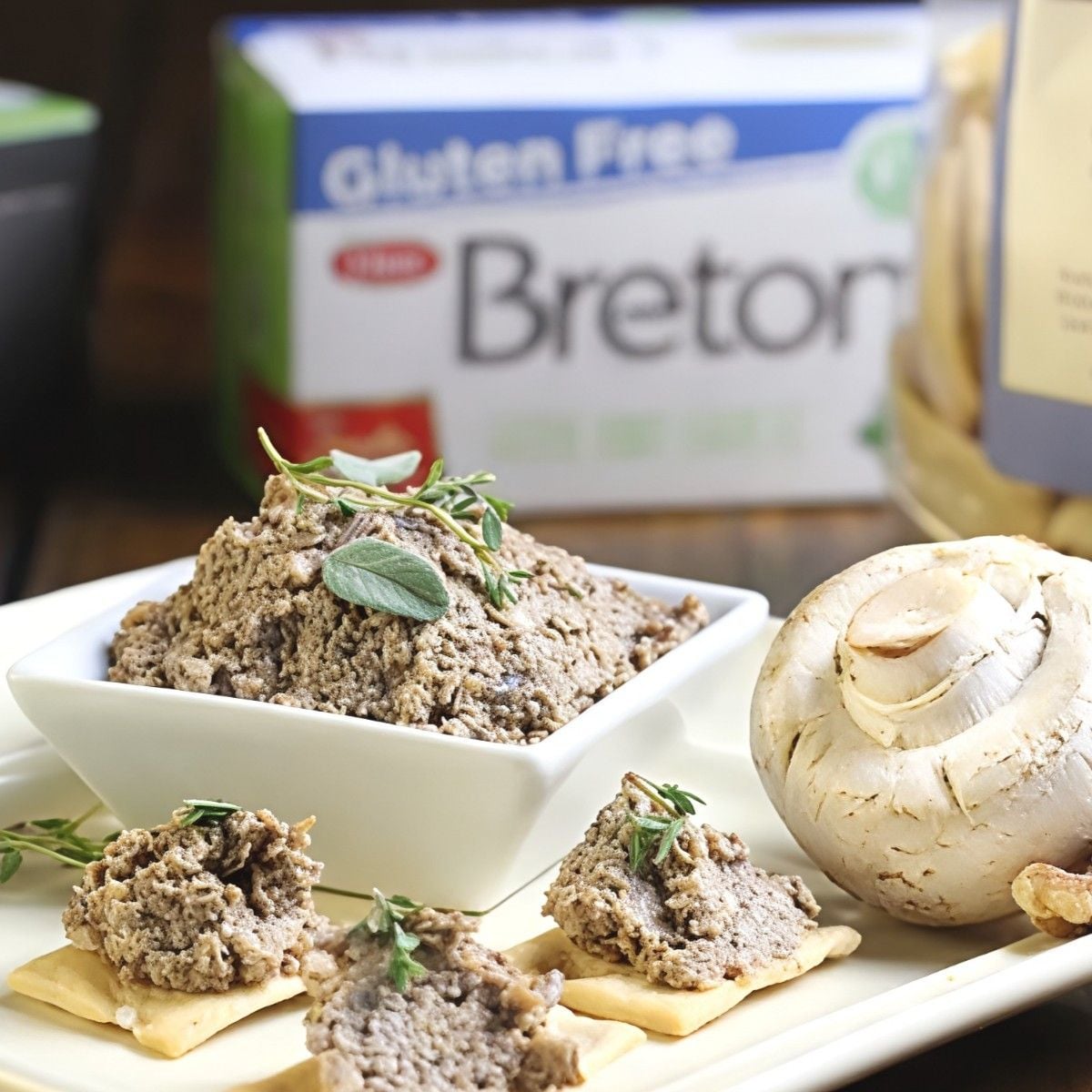 Creamy vegan mushroom walnut pate served on crackers with fresh herbs, perfect for vegan Thanksgiving appetizers.