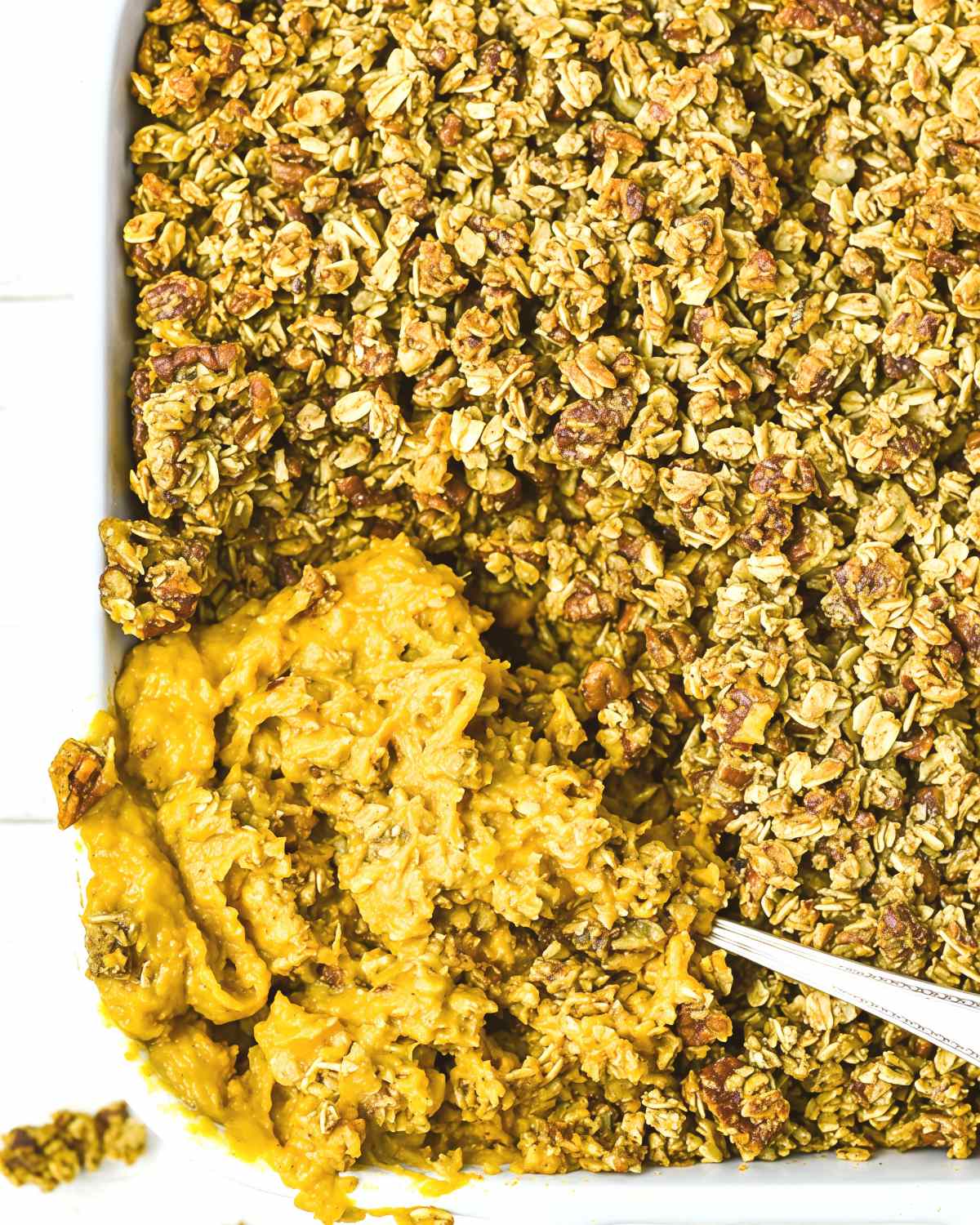 Vegan sweet potato casserole in a baking dish with a crispy oat and pecan crumble topping for a Thanksgiving side dish.